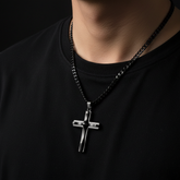 Black cross necklace on dark background - no face