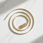 Gold chain belt in graceful spiral on marble