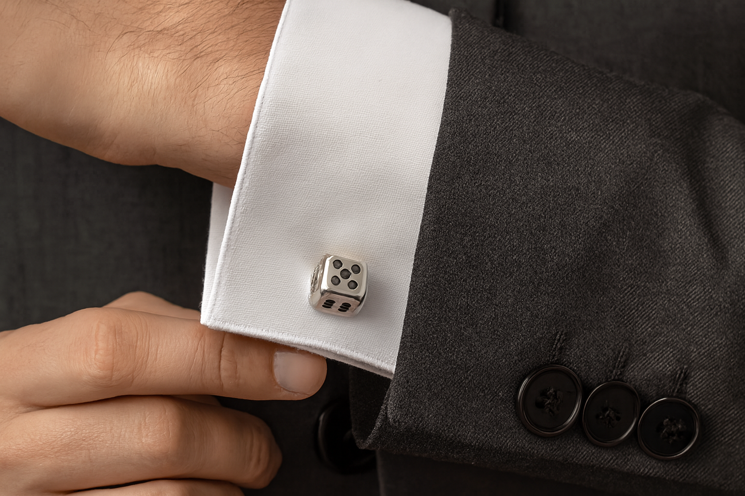 Silver dice cufflinks on charcoal gray suit close-up detail